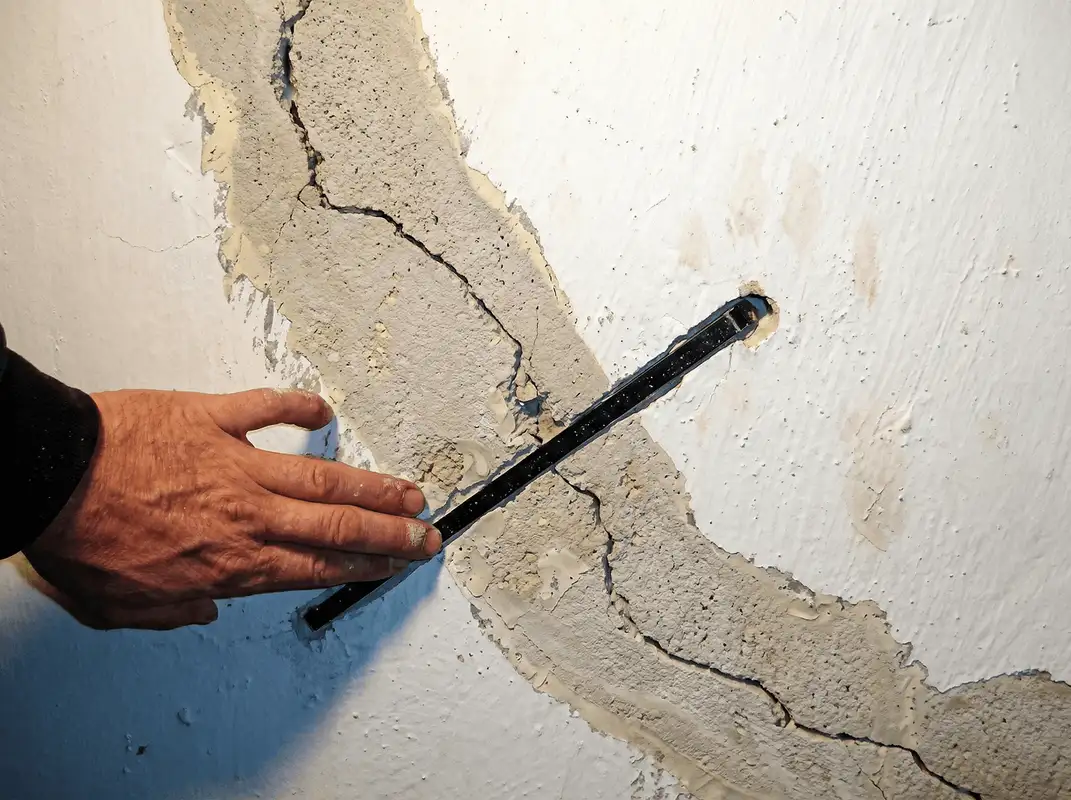 A wall with a large crack is being inspected by a professional in Henderson, NV