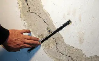 A wall with a large crack is being inspected by a professional in Henderson, NV